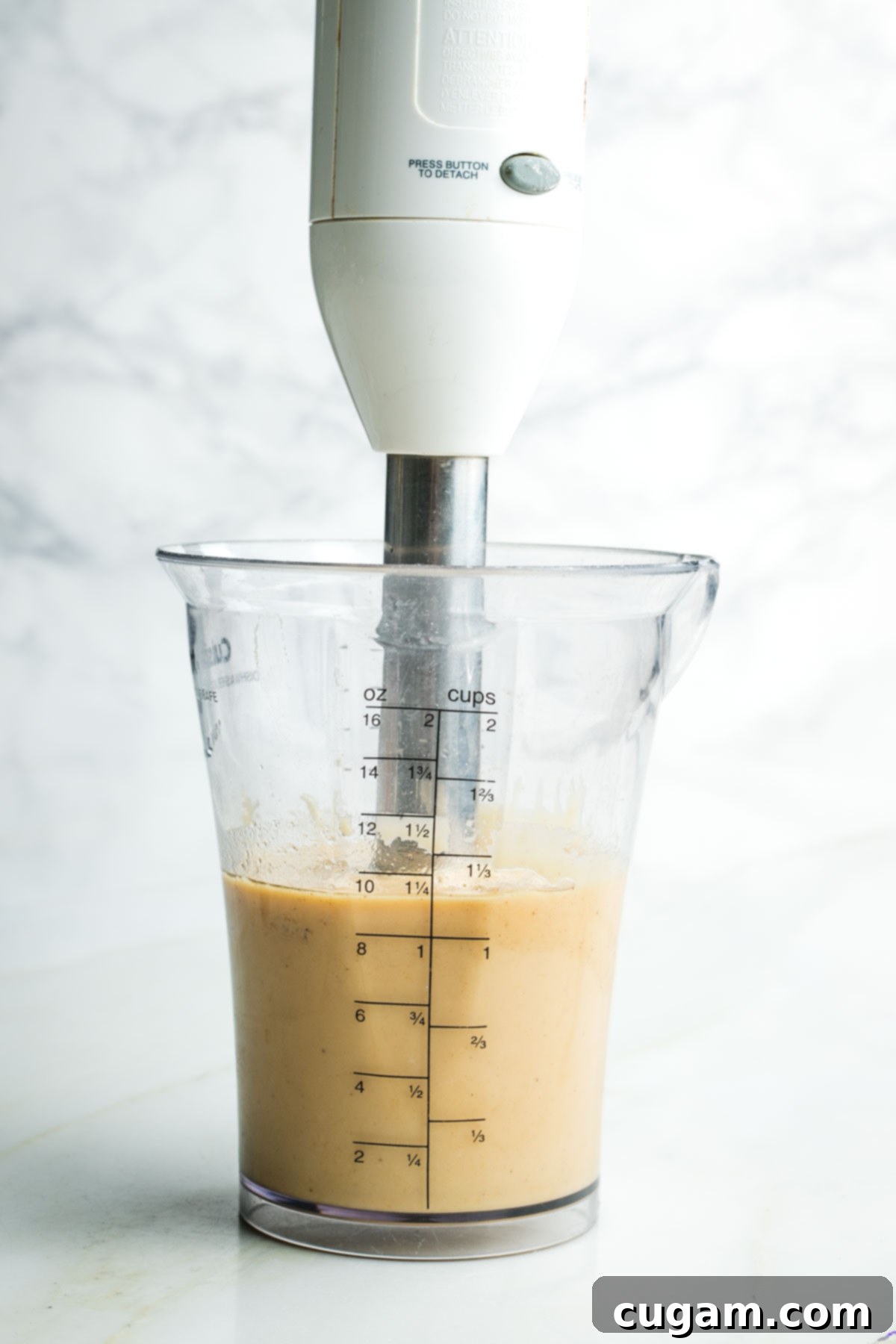 Crisp Raw Broccoli Salad with Miso Dressing 6 Immersion blender creating a creamy light tan dressing in a cup.