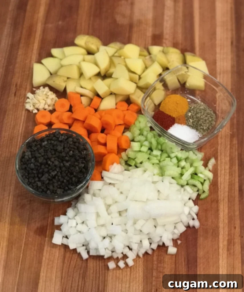 Ingredient shot for no beef stew: chunks of potatoes, carrots, celery and onions, a small glass dish of spices and another with dried black beluga lentils. 