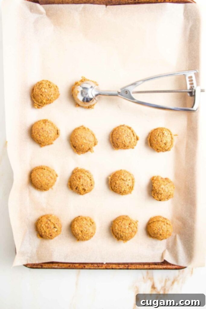 Using a small cookie scoop to portion out pumpkin balls.
