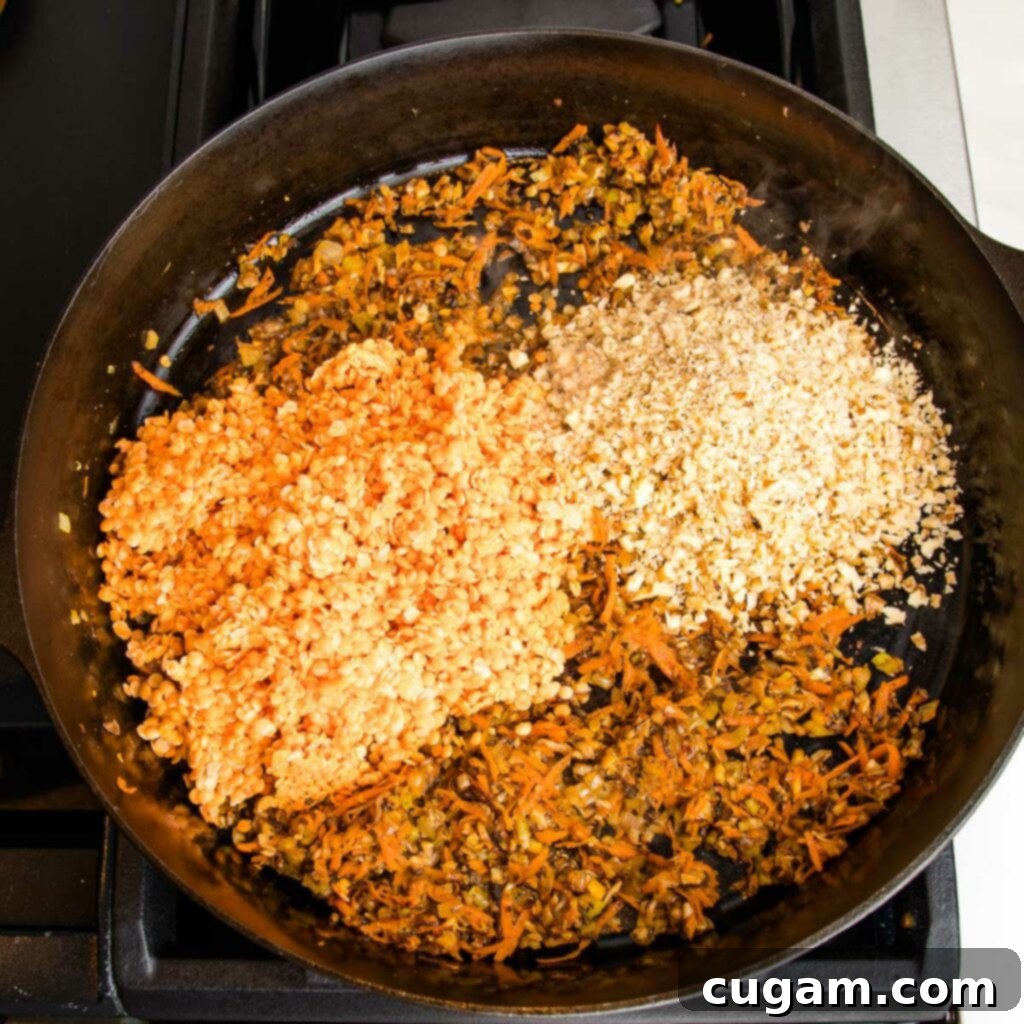Red lentils and finely chopped walnuts are added to a cast iron pan that is filled with sautéed mushrooms, carrots, celery, onions and spices.