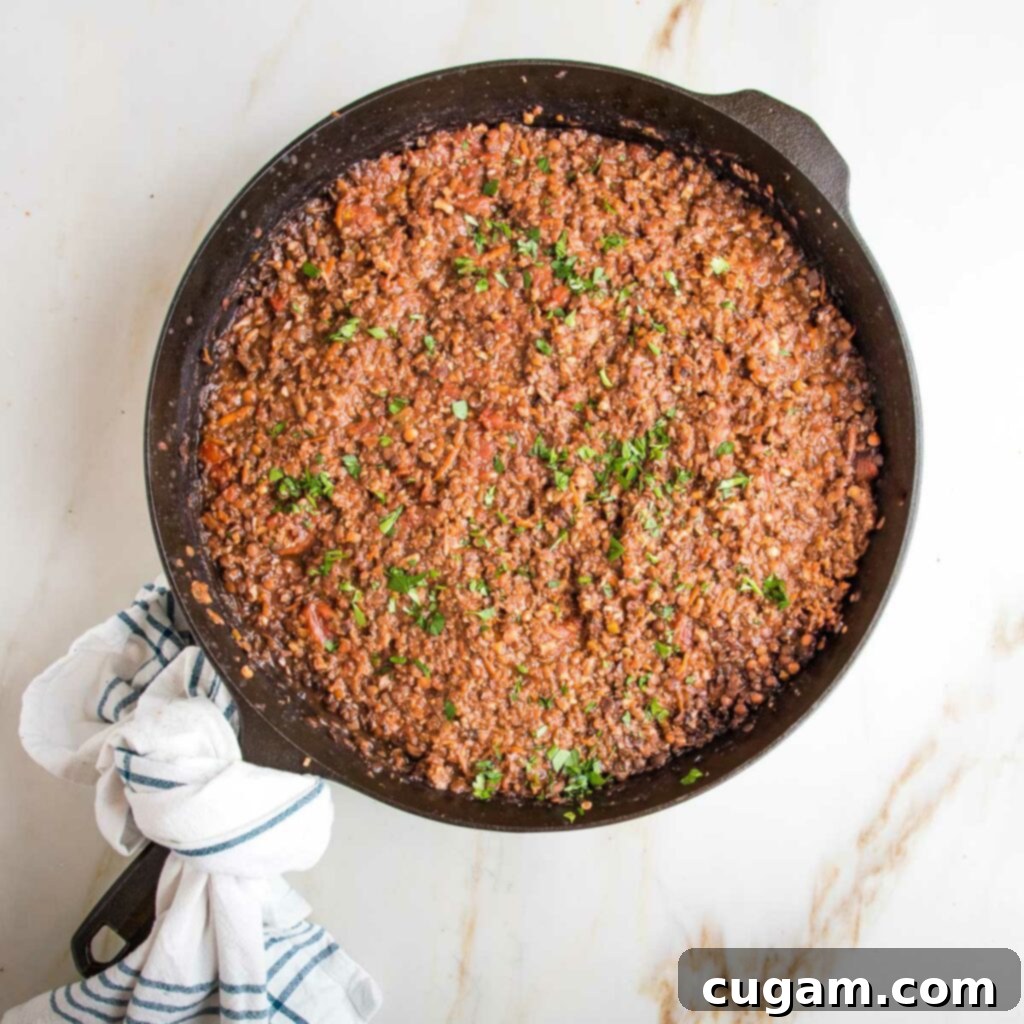 Vegan bolognese sauce inside a cast iron skillet, sprinkled with fresh parsley.