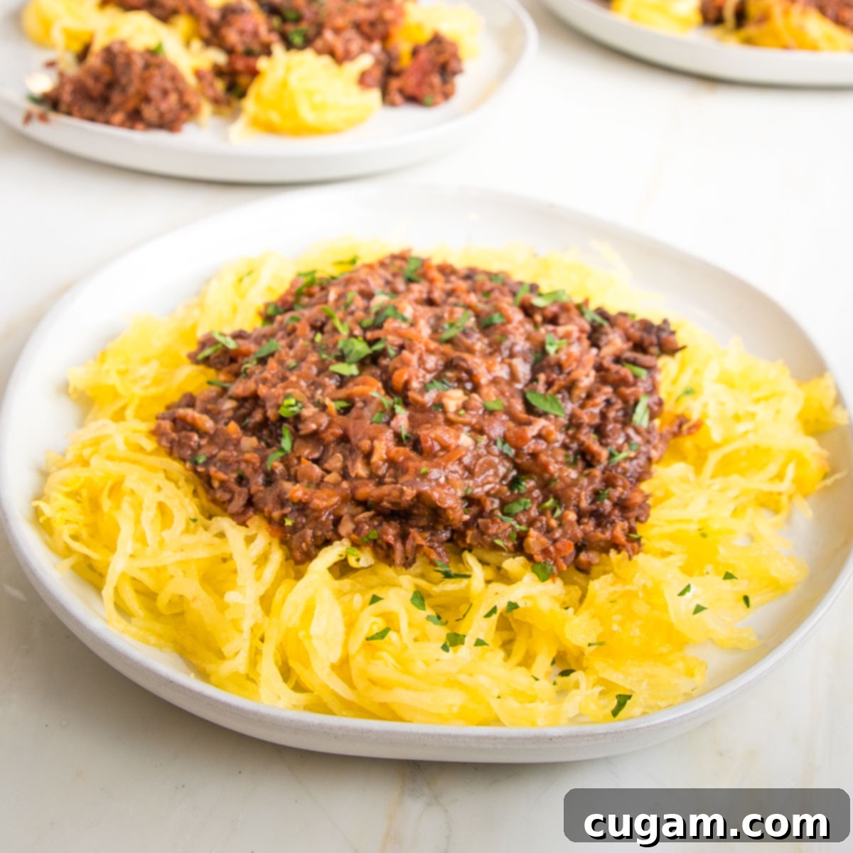 White plate with spaghetti squash topped with vegan bolognese