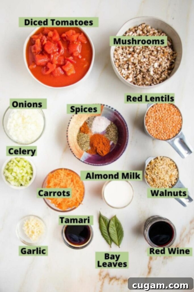 Ingredients for Vegan Bolognese laid out and labeled: diced tomatoes, diced mushrooms, onions, celery, garlic, shredded carrots, red lentils, almond milk, chopped walnuts, spices, red wine, almond milk, tamari and bay leaves.