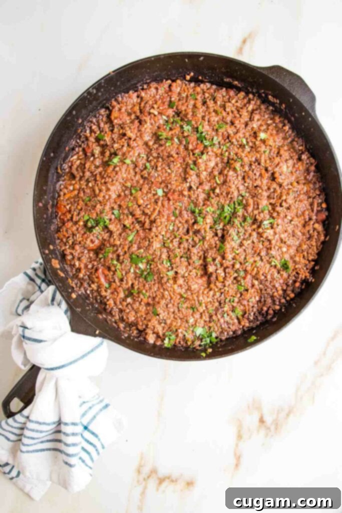 Red lentil and mushroom vegan bolognese in a cast iron skillet, sprinkled with fresh parsley.