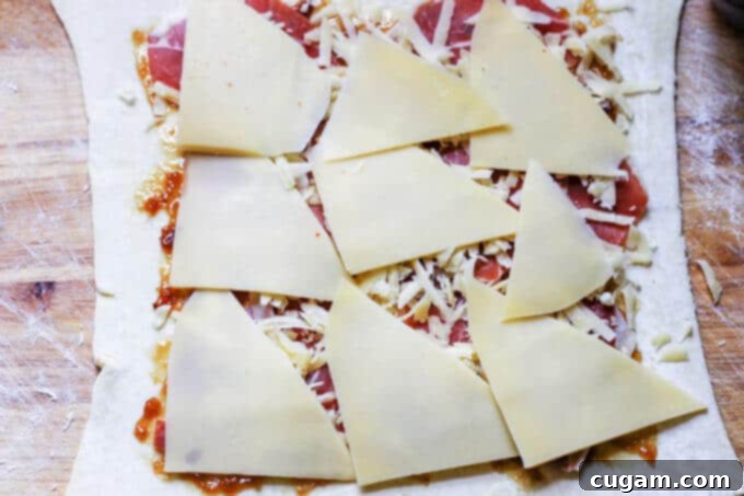 Adding sliced Semi-Cured Mahon-Menorca cheese as the final layer before rolling.