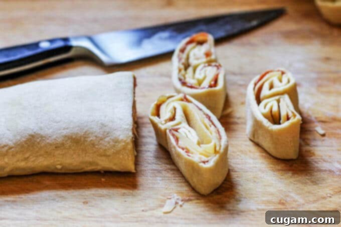 Sliced Mahon-Menorca Pinwheels on a baking sheet with parchment paper, ready for the oven.