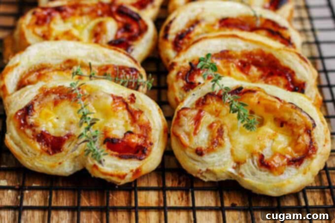 A close-up shot of two perfectly baked Mahon-Menorca Pinwheels on a rustic surface, invitingly golden and flaky.