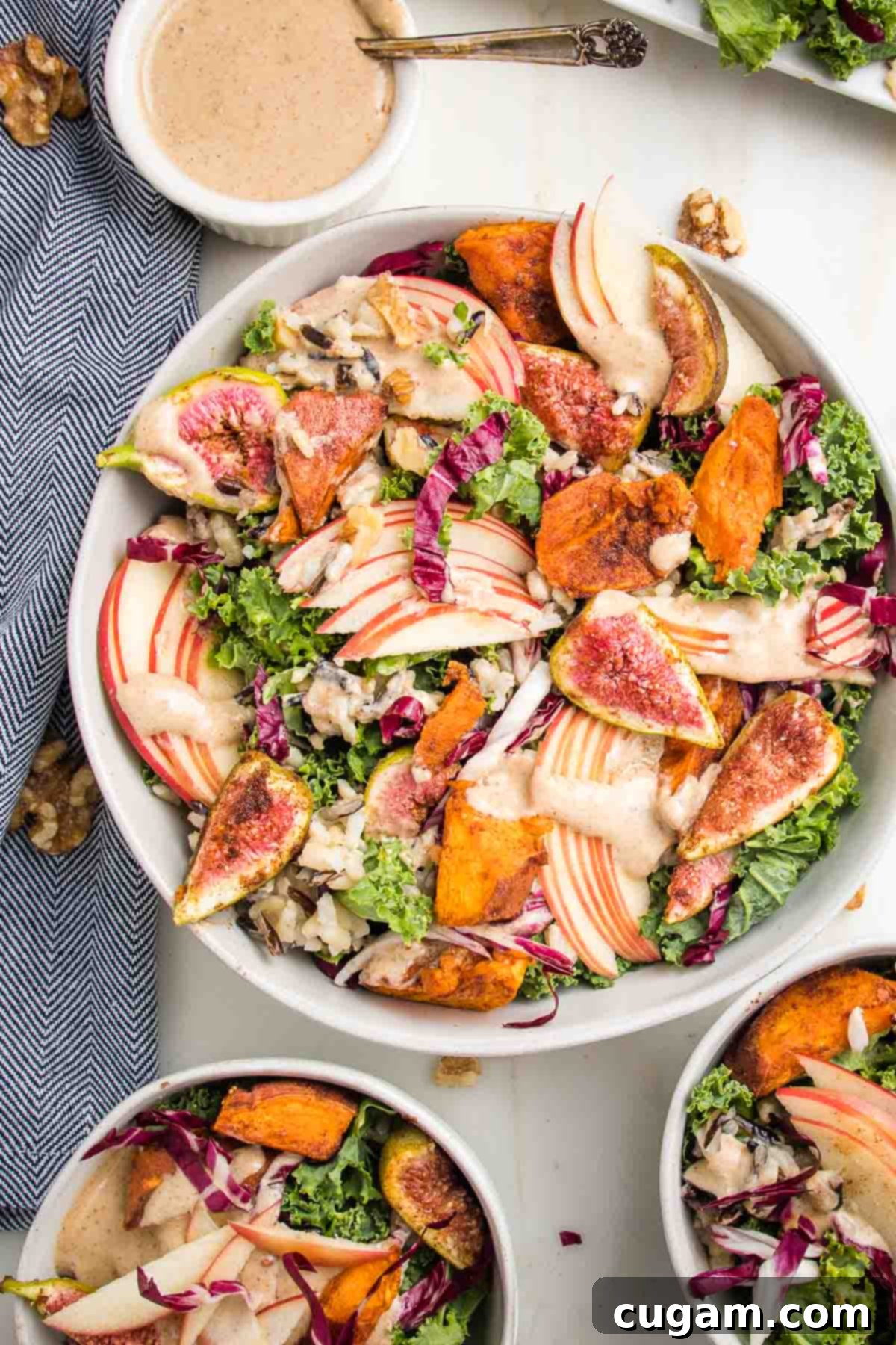 Large bowl of kale salad, loaded with roasted sweet potatoes and figs, sliced apples, wild rice and drizzled with apple vinaigrette.