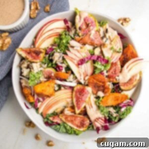Large white bowl with kale and apple salad, roasted sweet potatoes and figs plus apple vinaigrette