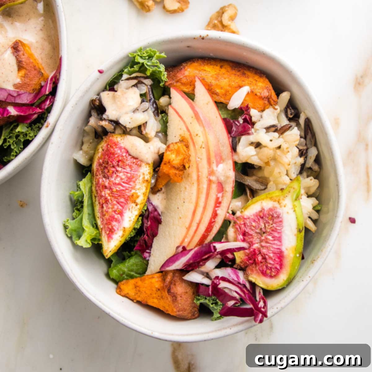 Small bowl with greens, figs, roasted sweet potatoes, sliced apples and a creamy dressing.