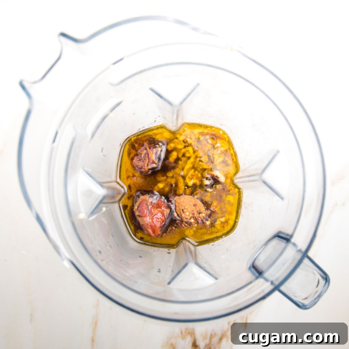 Ingredients for a fall dressing in the pitcher of a blender: oil, vinegar, walnuts, spices, dates, mustard are visible.