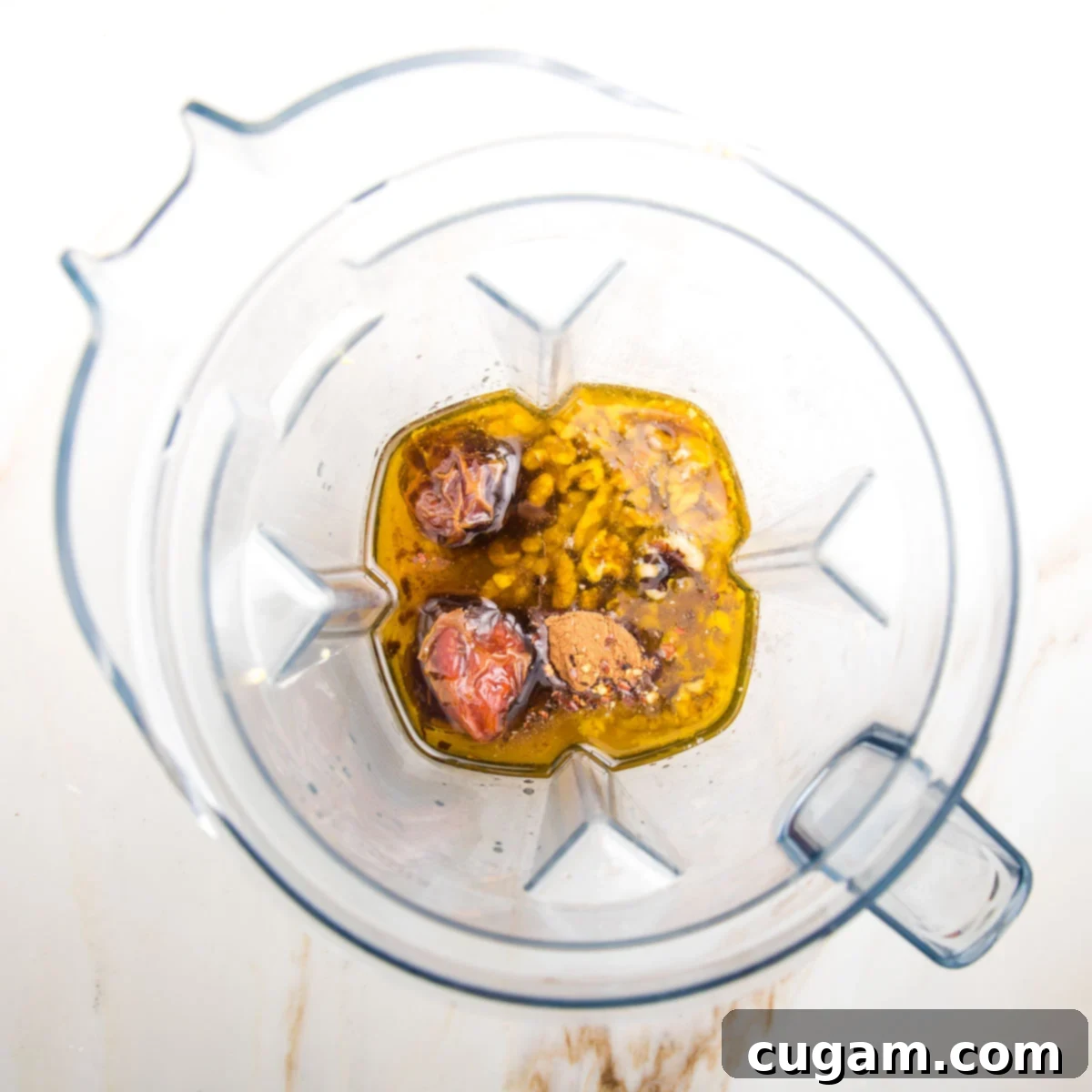 Ingredients for a fall dressing in the pitcher of a blender: oil, vinegar, walnuts, spices, dates, mustard are visible.