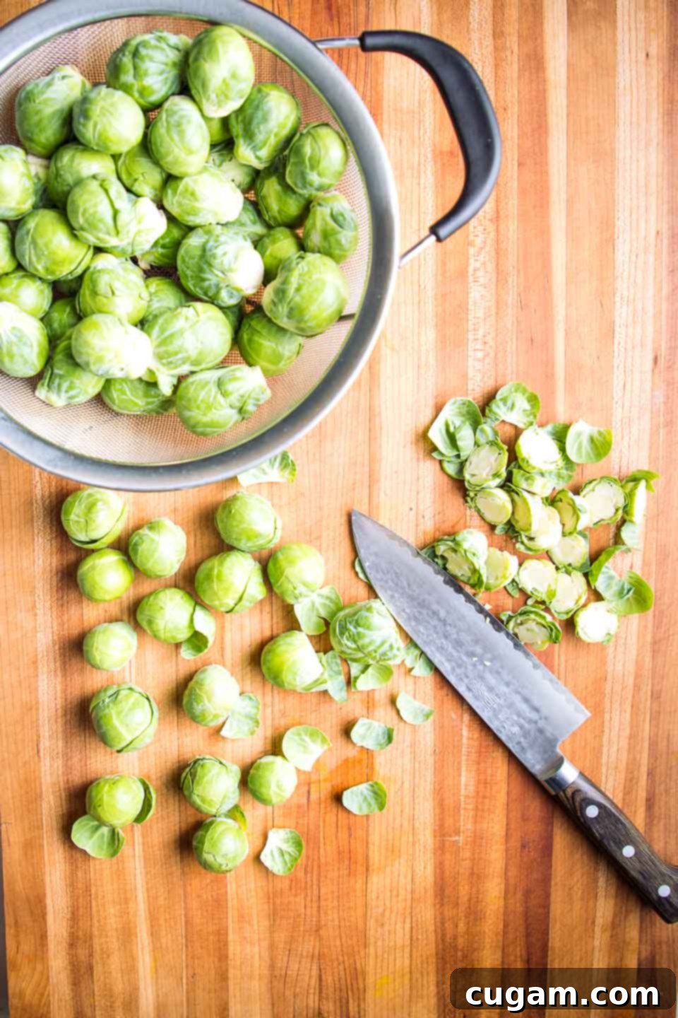 Colander of brussels sprouts, butting board trimming them with a sharp knife.