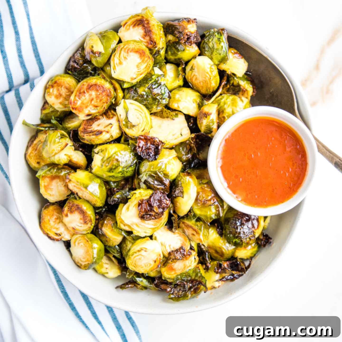 Close up of crispy brussels sprouts with a few stray leaves and a lime wedge.