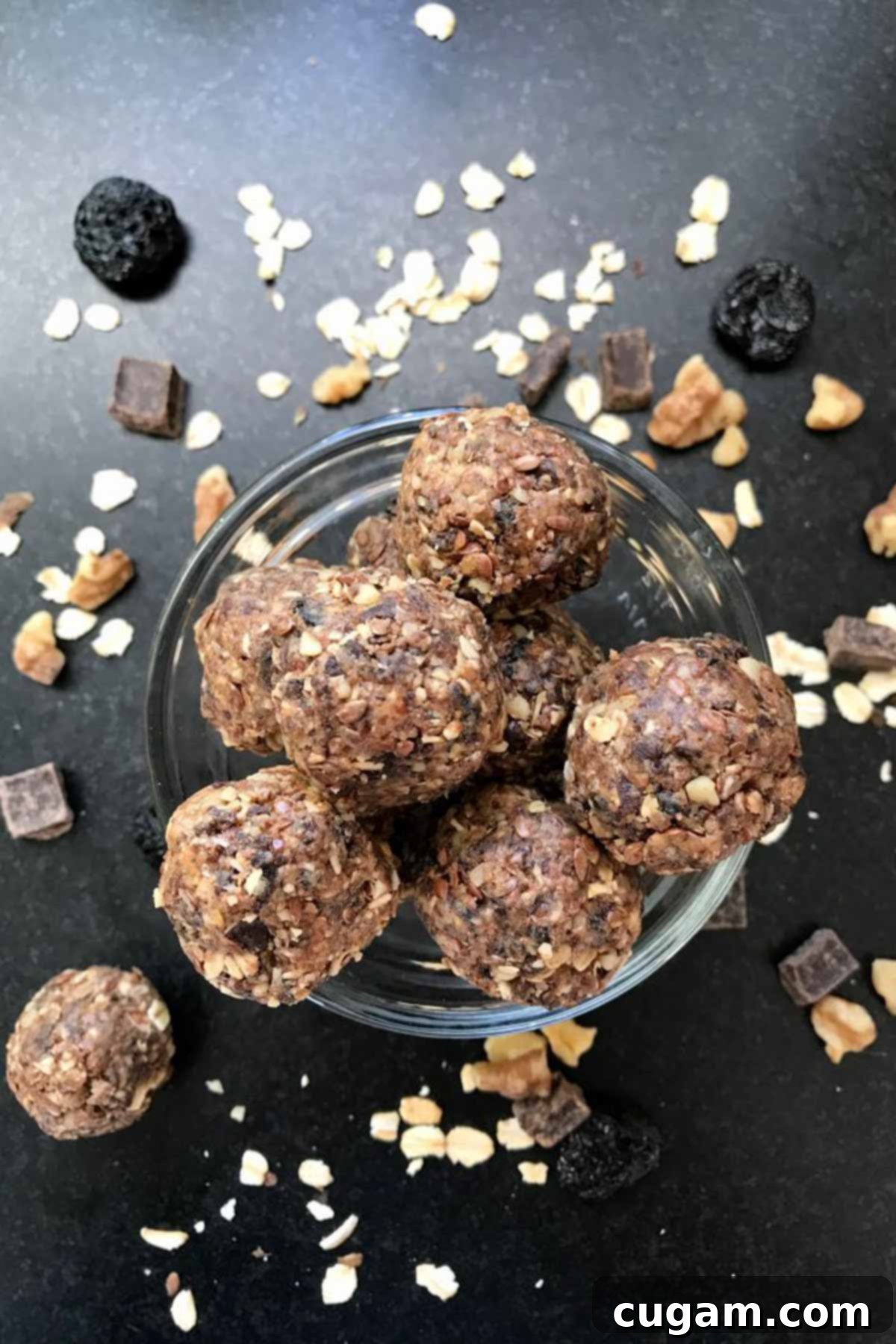 A top-down view of rolled energy balls made from oats, nuts, seeds, and dates, presented artfully on a surface.