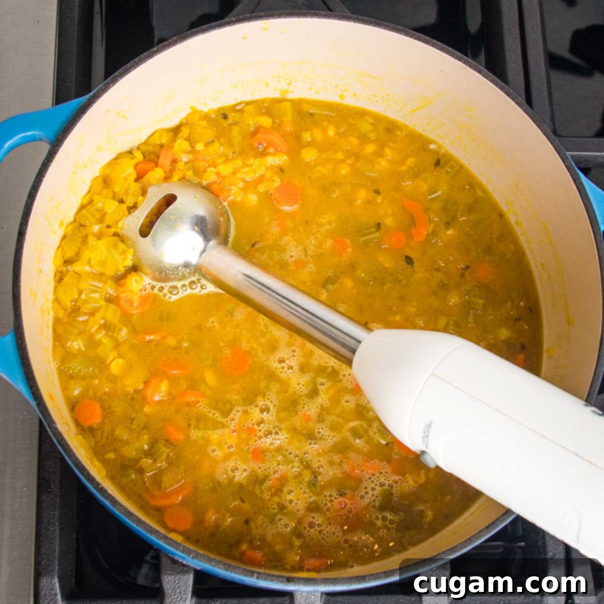 Dutch oven filled with chunky soup and an immersion blender.