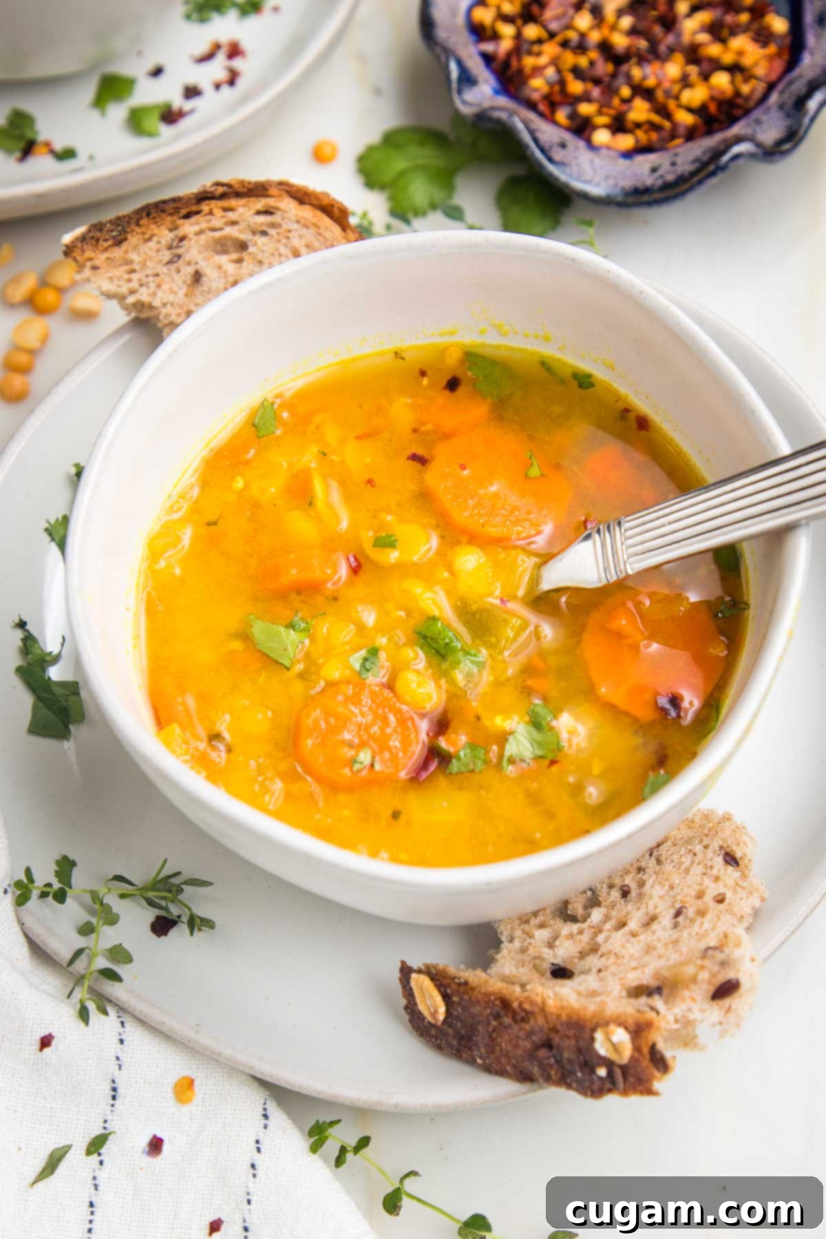 Bowl of yellow split pea soup with crusty bread.
