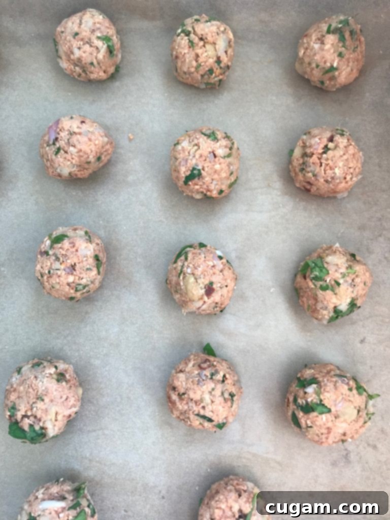 Perfectly rolled Vegan Sweet and Sour Meatballs arranged neatly on a baking sheet, ready for the oven.