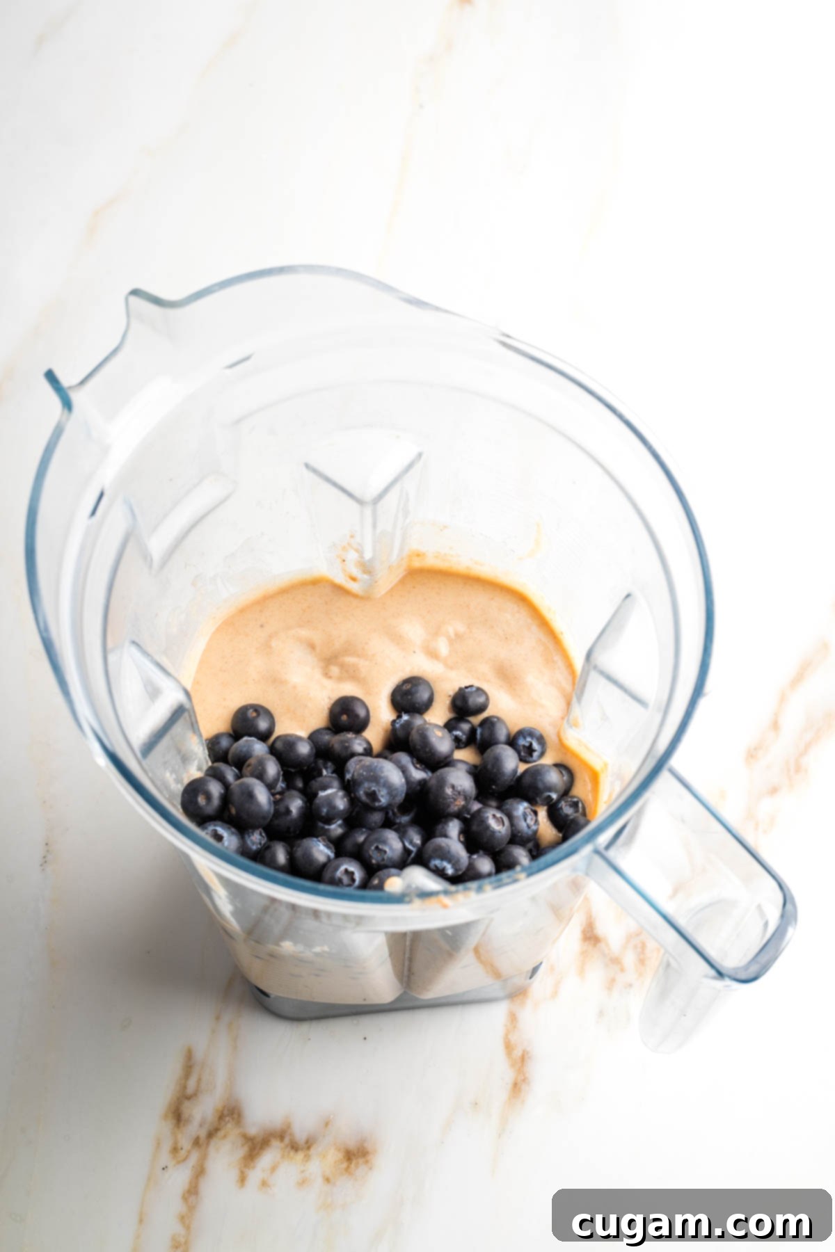 Smooth, light-colored muffin batter in a blender pitcher, ready for the next step.