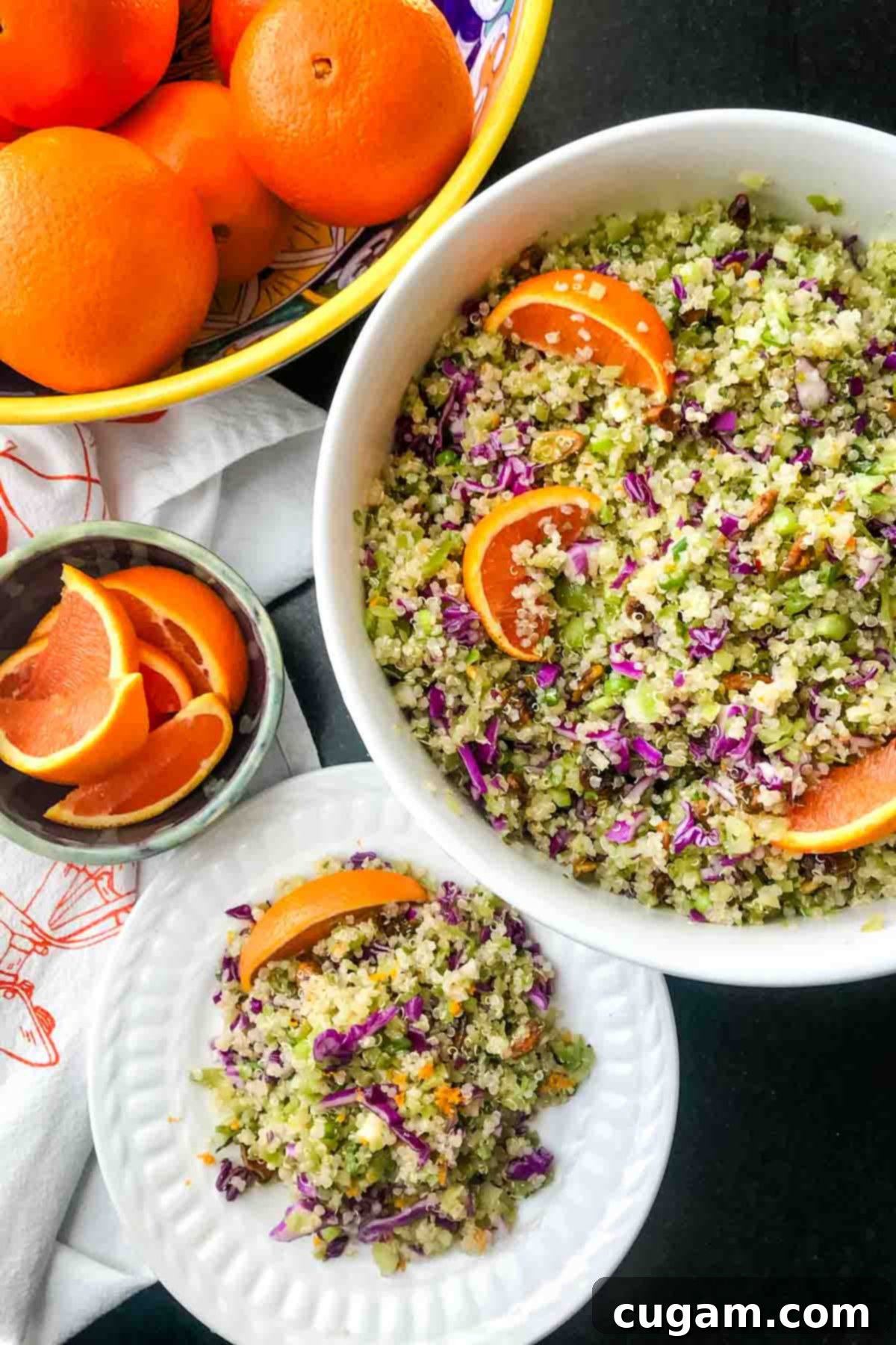 A vibrant bowl of Riced Broccoli and Quinoa Salad, featuring purple cabbage, pistachios, and fresh orange wedges. It's a colorful and healthy vegan meal.