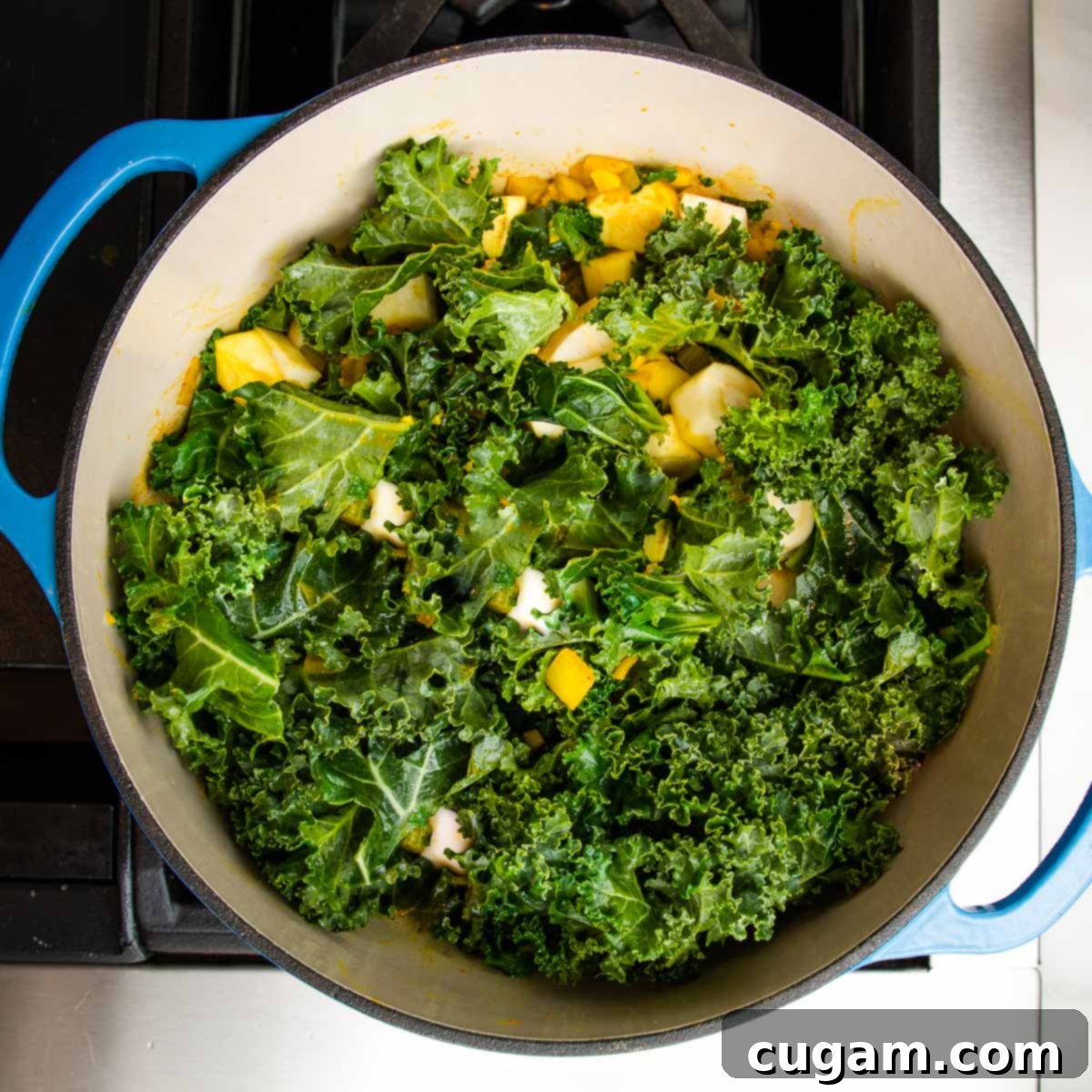 Wilted kale and tender parsnips mingling with sautéed onions and spices in a Dutch oven, illustrating the vegetables softening before the broth is added for simmering.