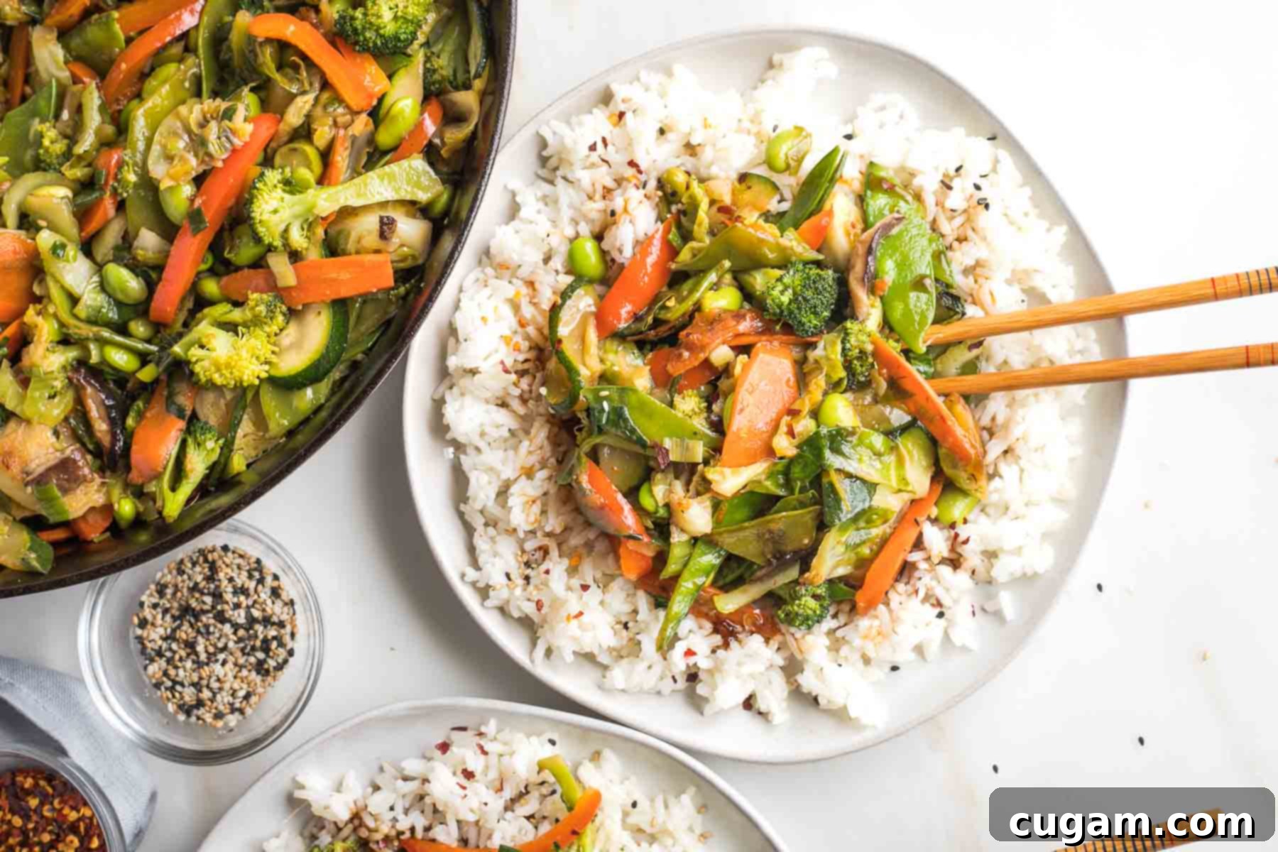 Pan of stir fry veggies, plus a plate of rice topped with the teriyaki vegetables, ready to be served.