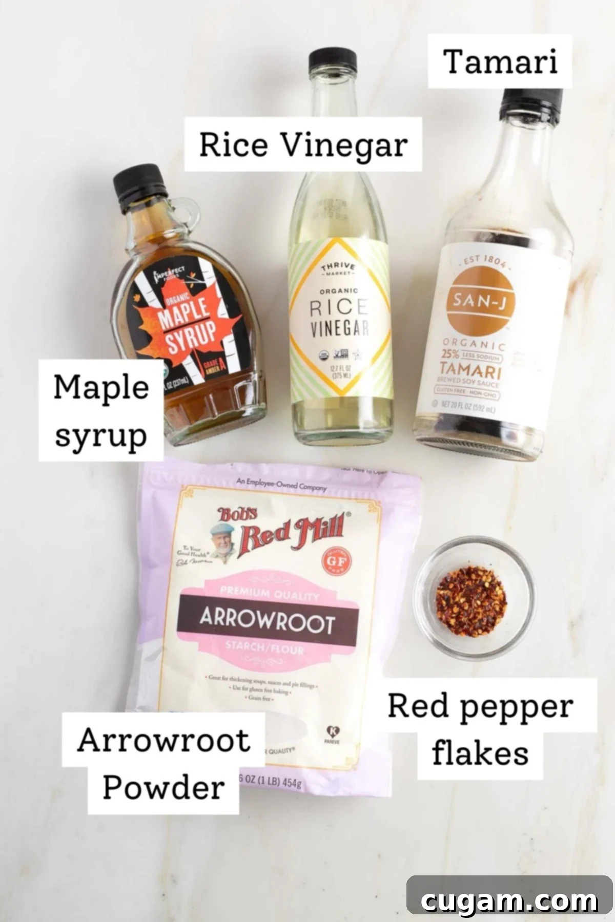 Labeled ingredients for teriyaki sauce: tamari, rice vinegar, maple syrup, arrowroot powder, red pepper flakes, neatly arranged on a cutting board.