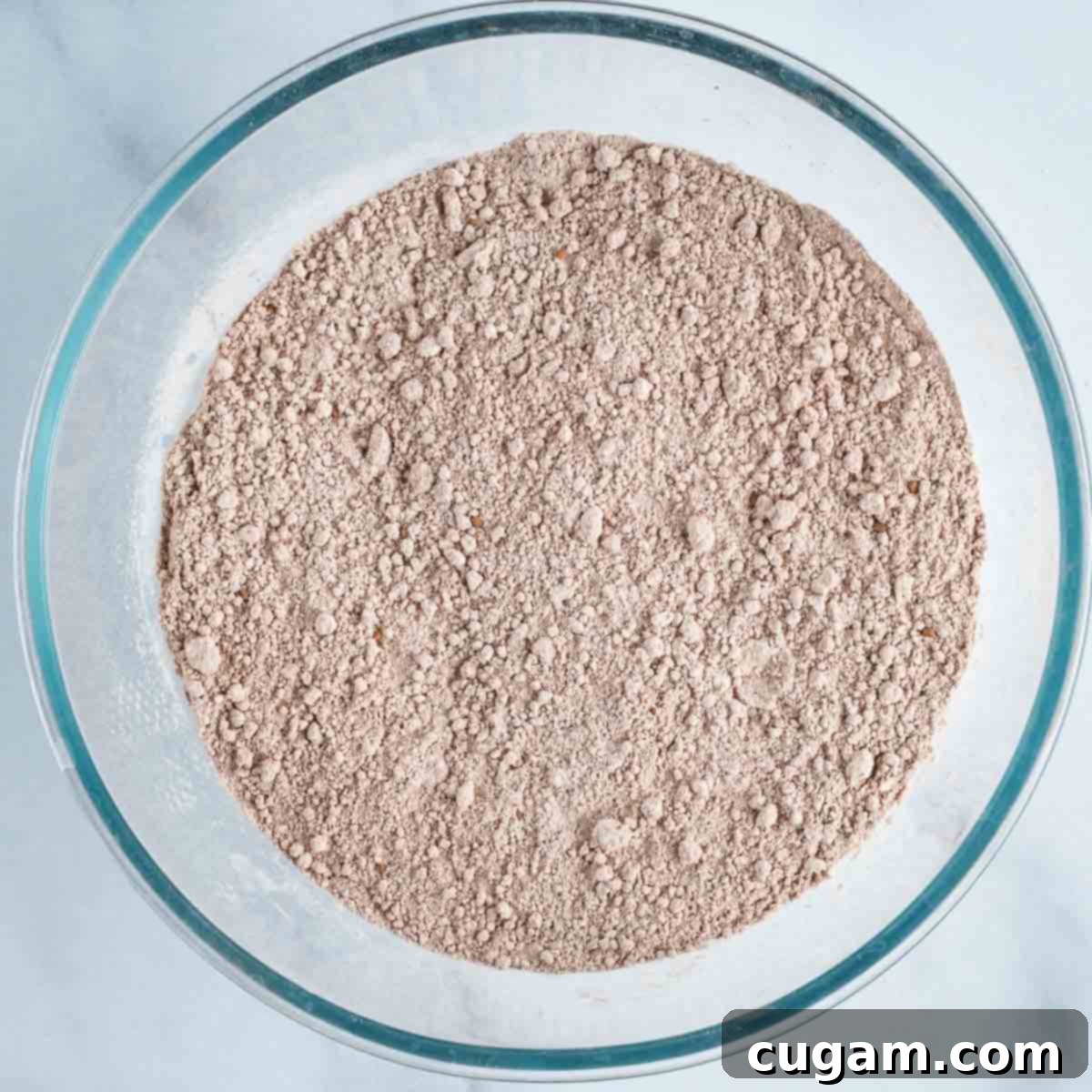 Chocolate powdery dry ingredients mixed together in a glass bowl.