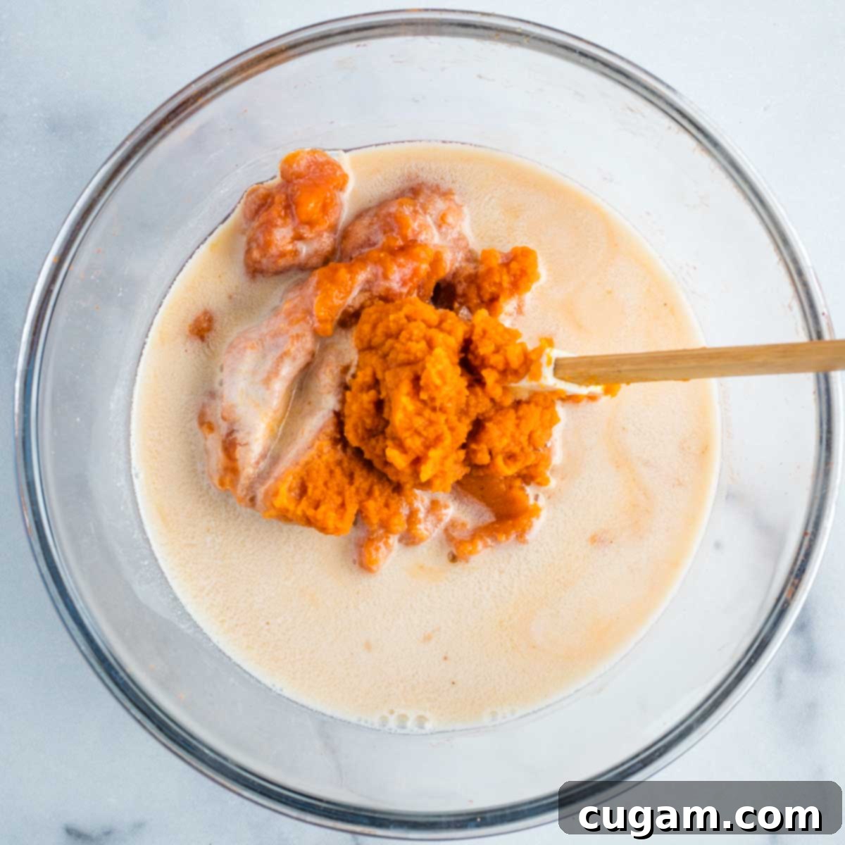 Pumpkin, applesauce, maple syrup and almond milk in a glass bowl.