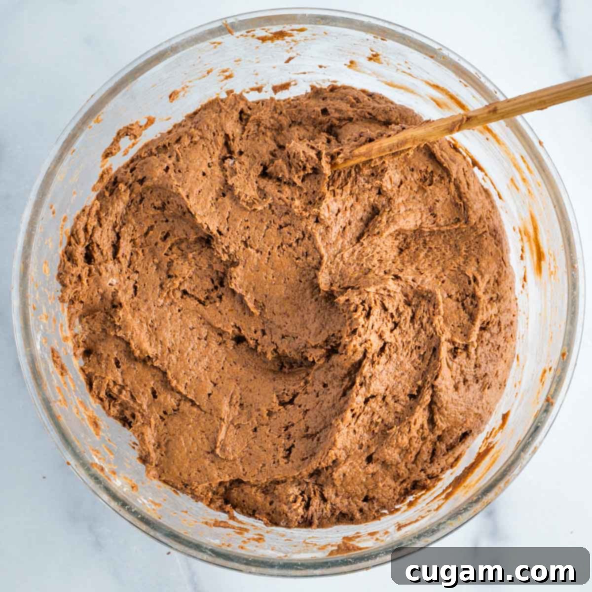 Chocolate muffin batter in a glass mixing bowl.