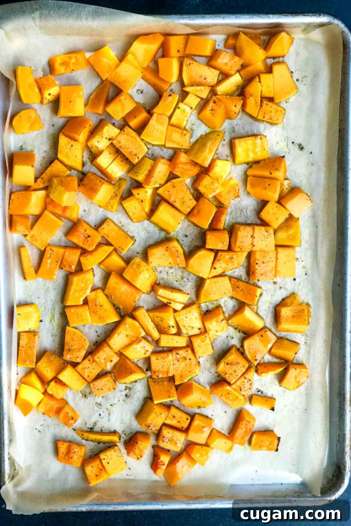 Roasted cubes of butternut squash on a rimmed baking tray.