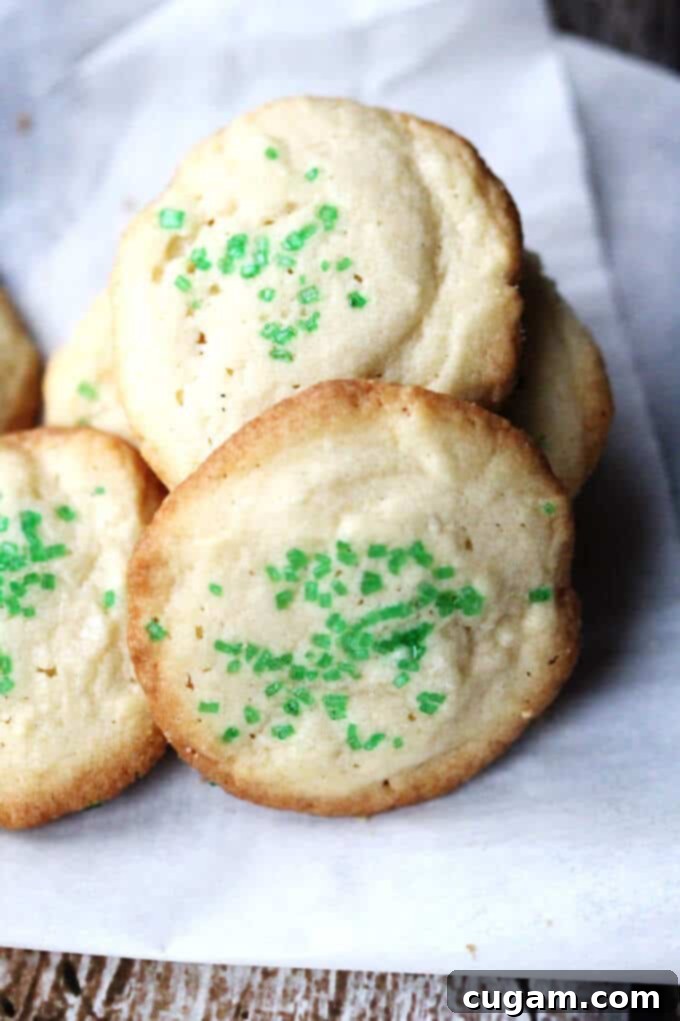 Freshly baked 5-Ingredient Butter Vanilla Cookies, adorned with green sprinkles, arranged on a cooling rack, showcasing their golden-brown edges.