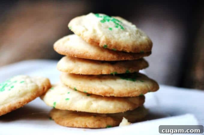 A festive close-up of 5-Ingredient Butter Vanilla Cookies with green sprinkles, arranged on a plate with a holiday ornament, ready for celebration.