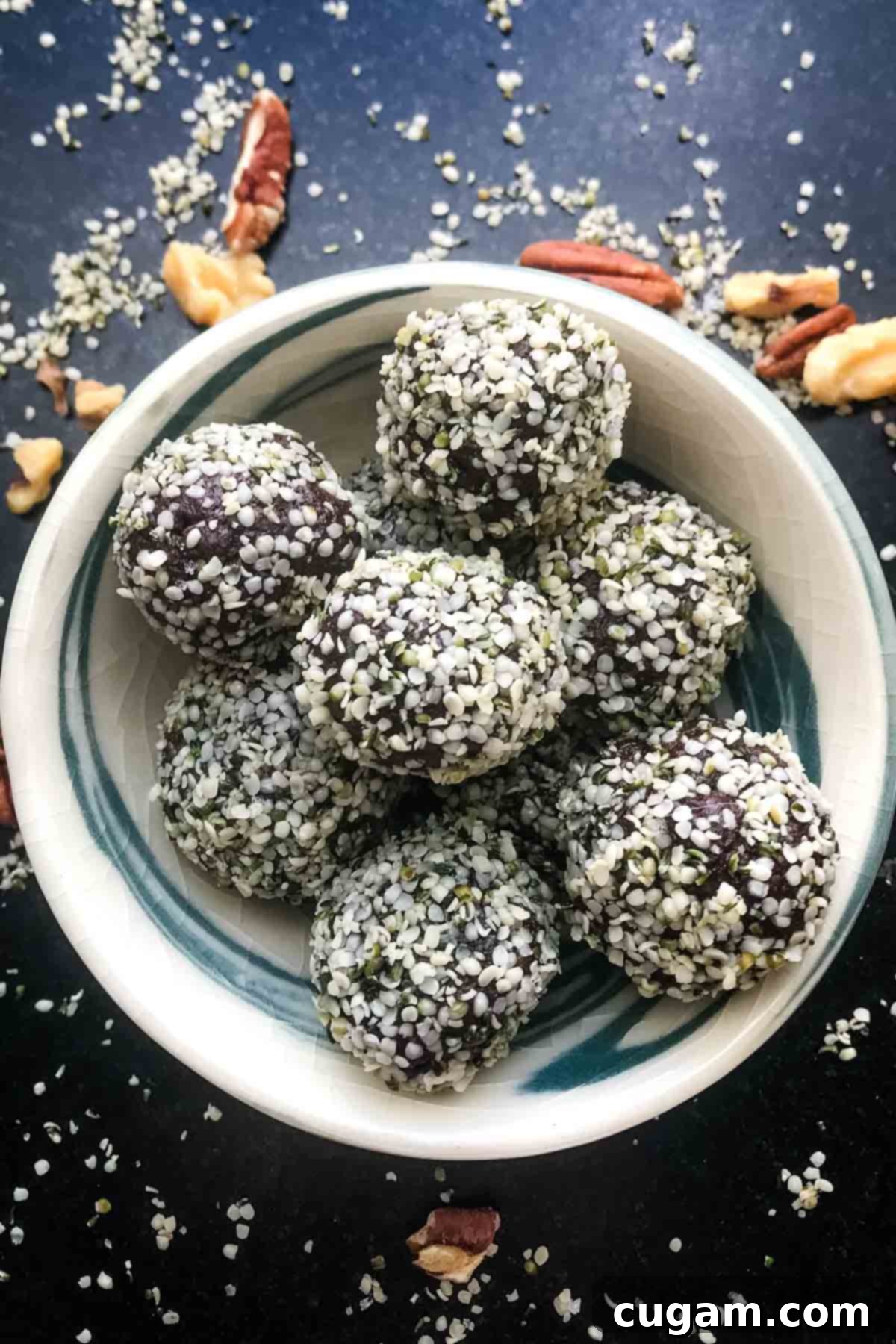 Chocolate balls dipped in hemp seeds, in a bowl with walnuts and hemp seeds scattered around the counter.