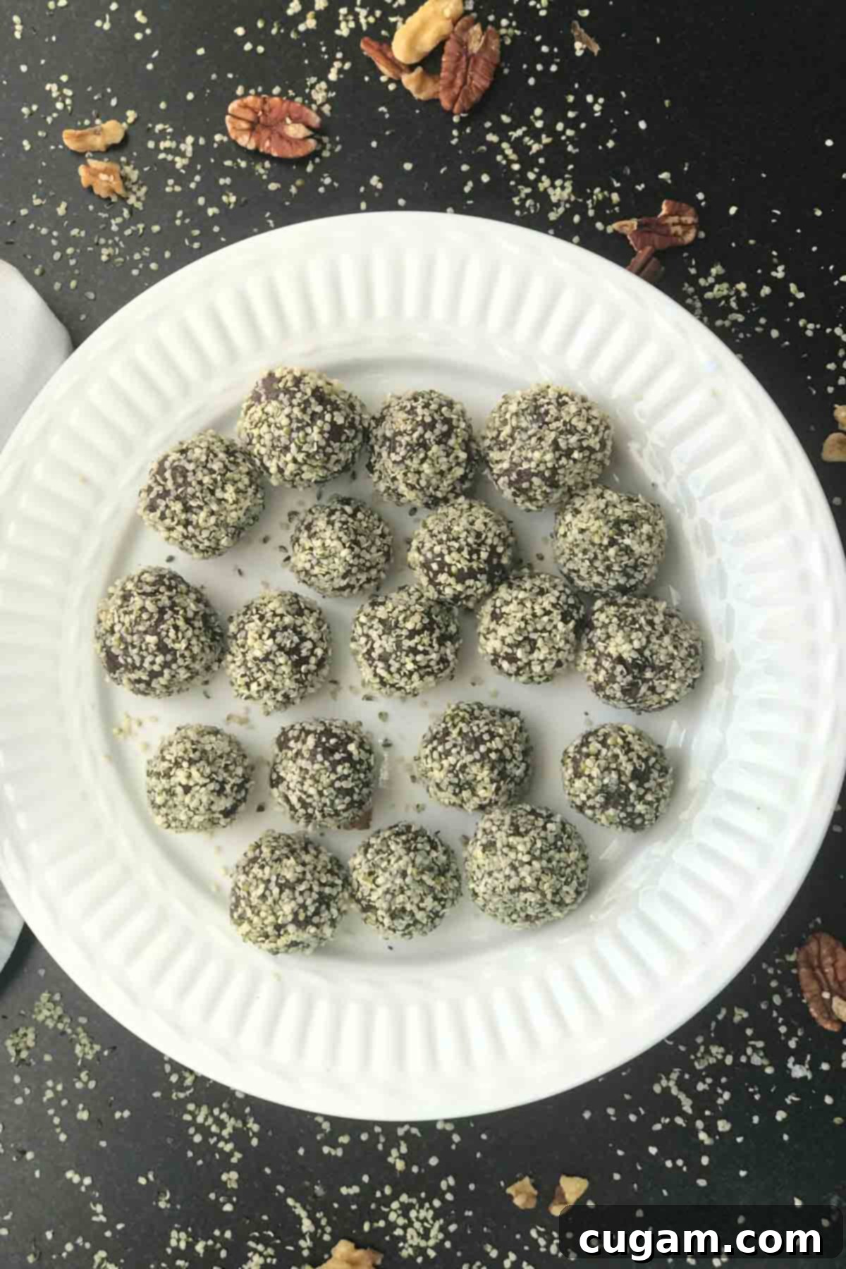 Plate full of chocolate balls that are coated in white hemp seeds.