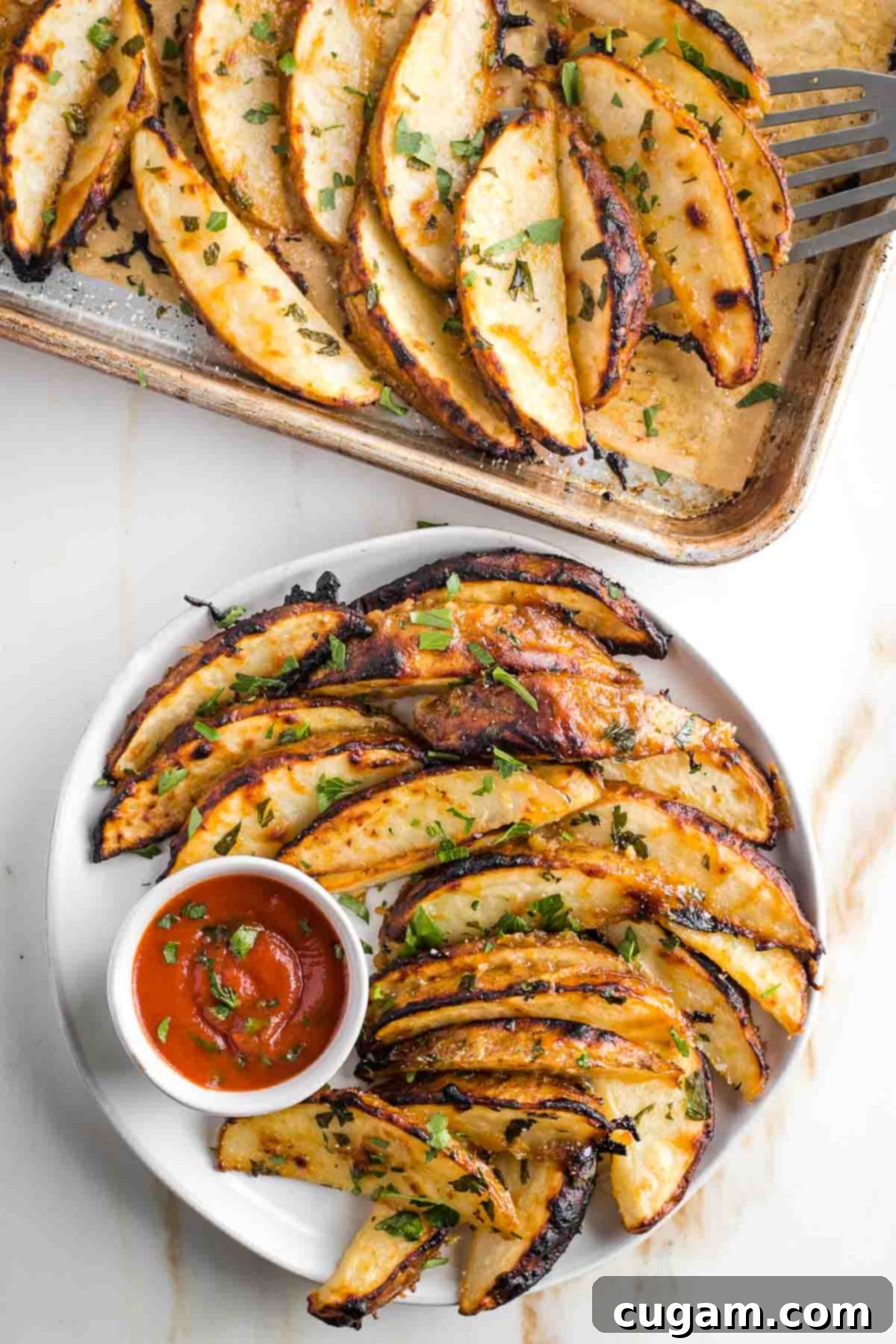 Crispy potato wedges on a plate with some ketchup, sprinkled with fresh herbs. 