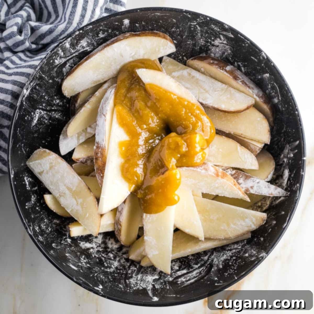 Bowl of potato wedges coated in arrowroot with a miso mixture on top.