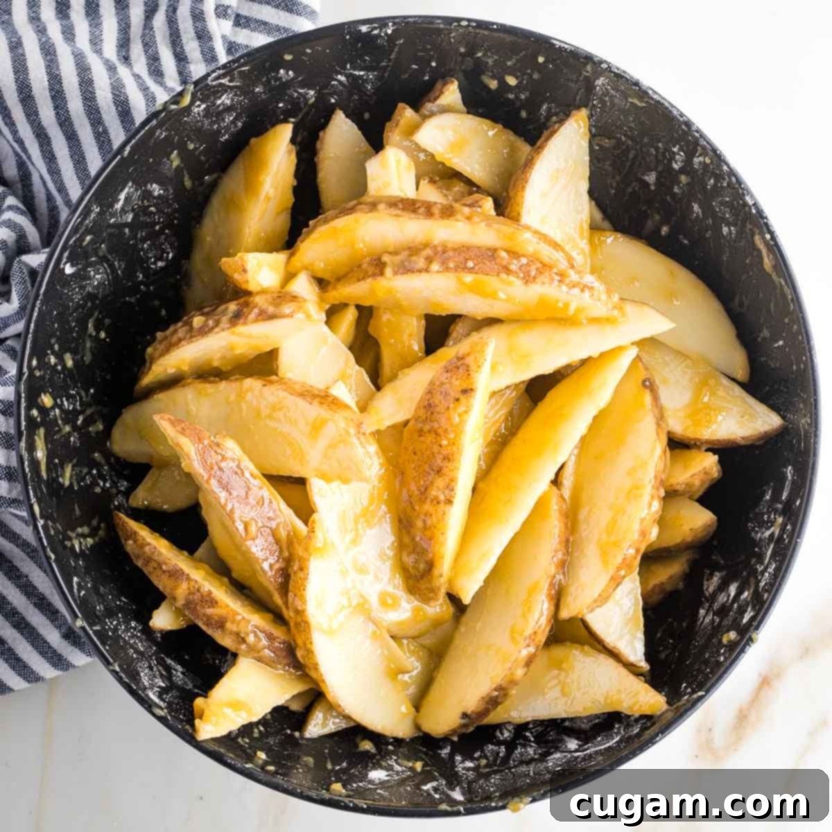 Potato wedges in a bowl with brown marinade.