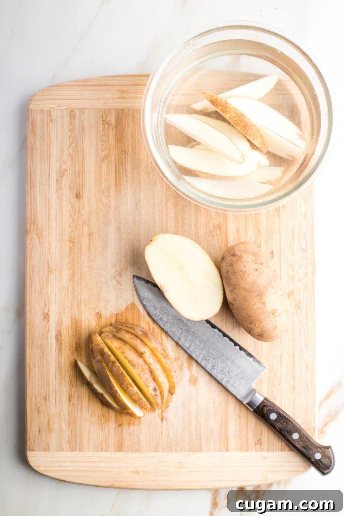 Demo on cutting potato into halves, then wedges and into a bowl of water.