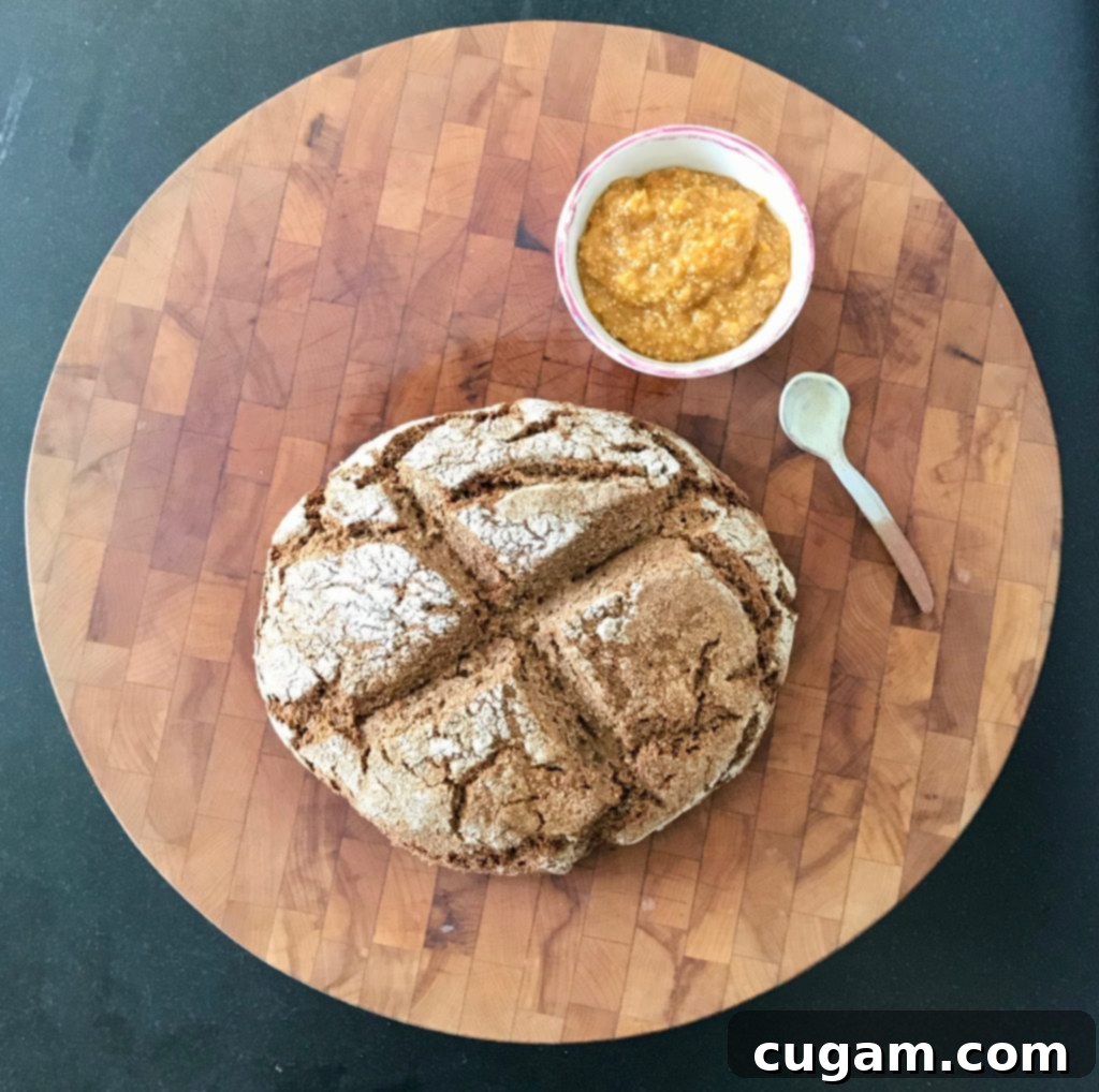 Gorgeous crusty loaf of Whole Grain Irish Soda Bread with a side of vibrant orange marmalade