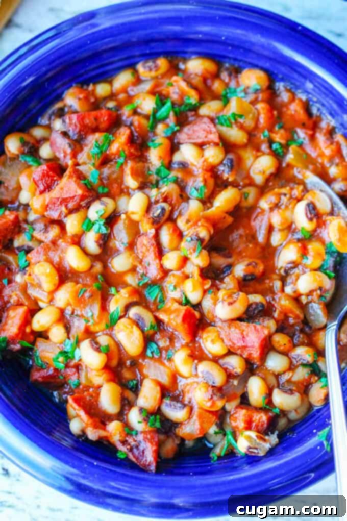 Close up photo of breton beans with sausage and tomatoes on blue plate with spoon