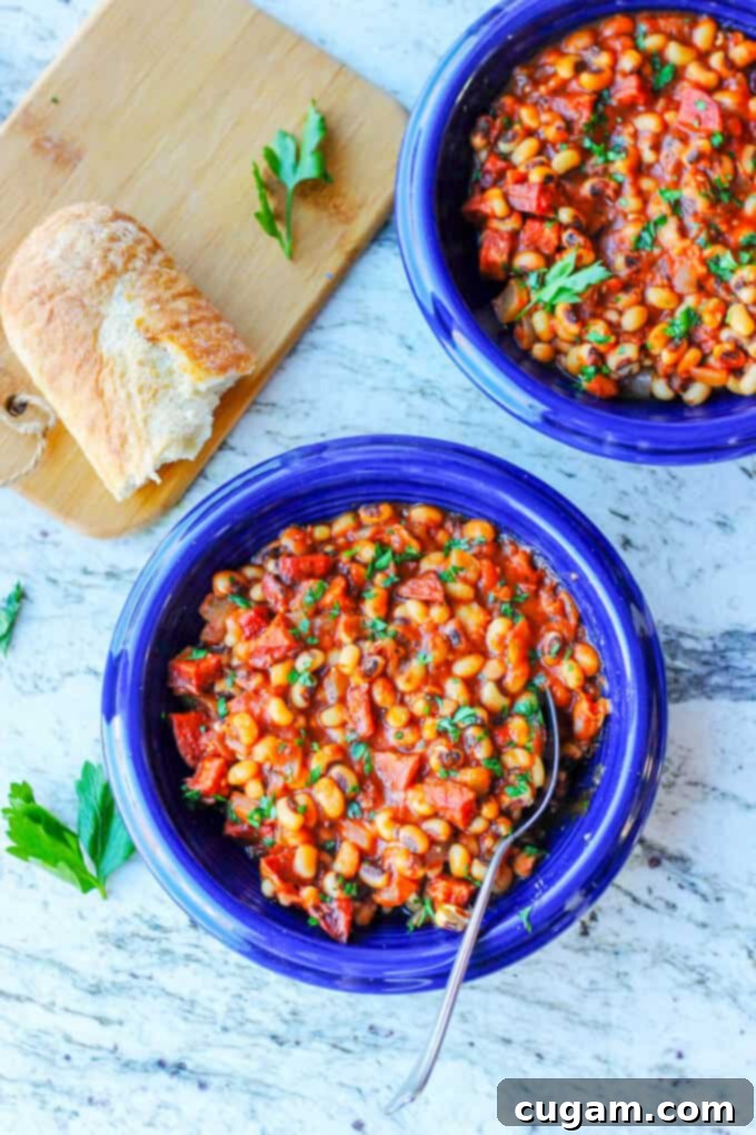 Two blue plates with breton beans, sausage and tomatoes; piece of bread on a cutting board