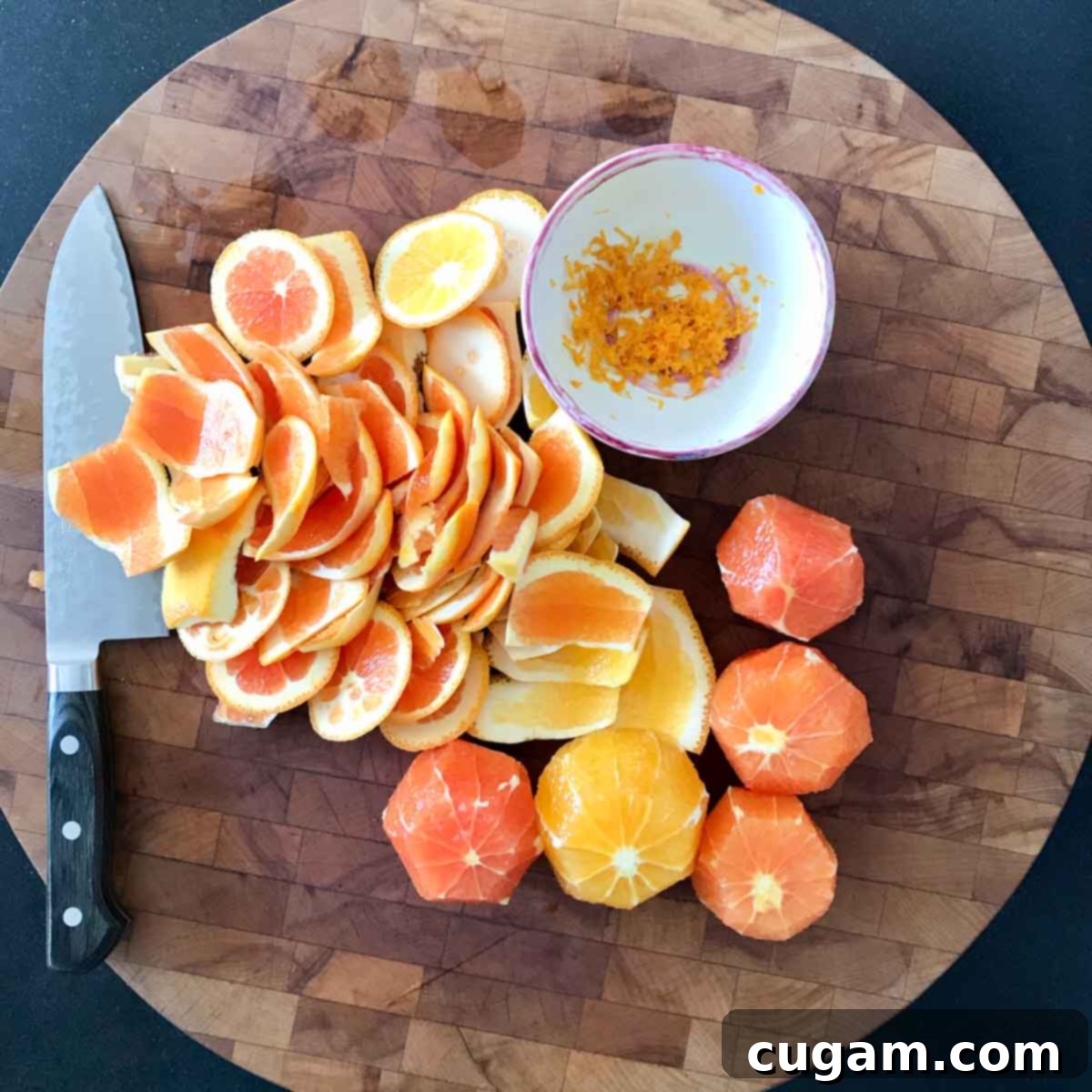 Cutting peels off oranges with a knife on a cutting board.