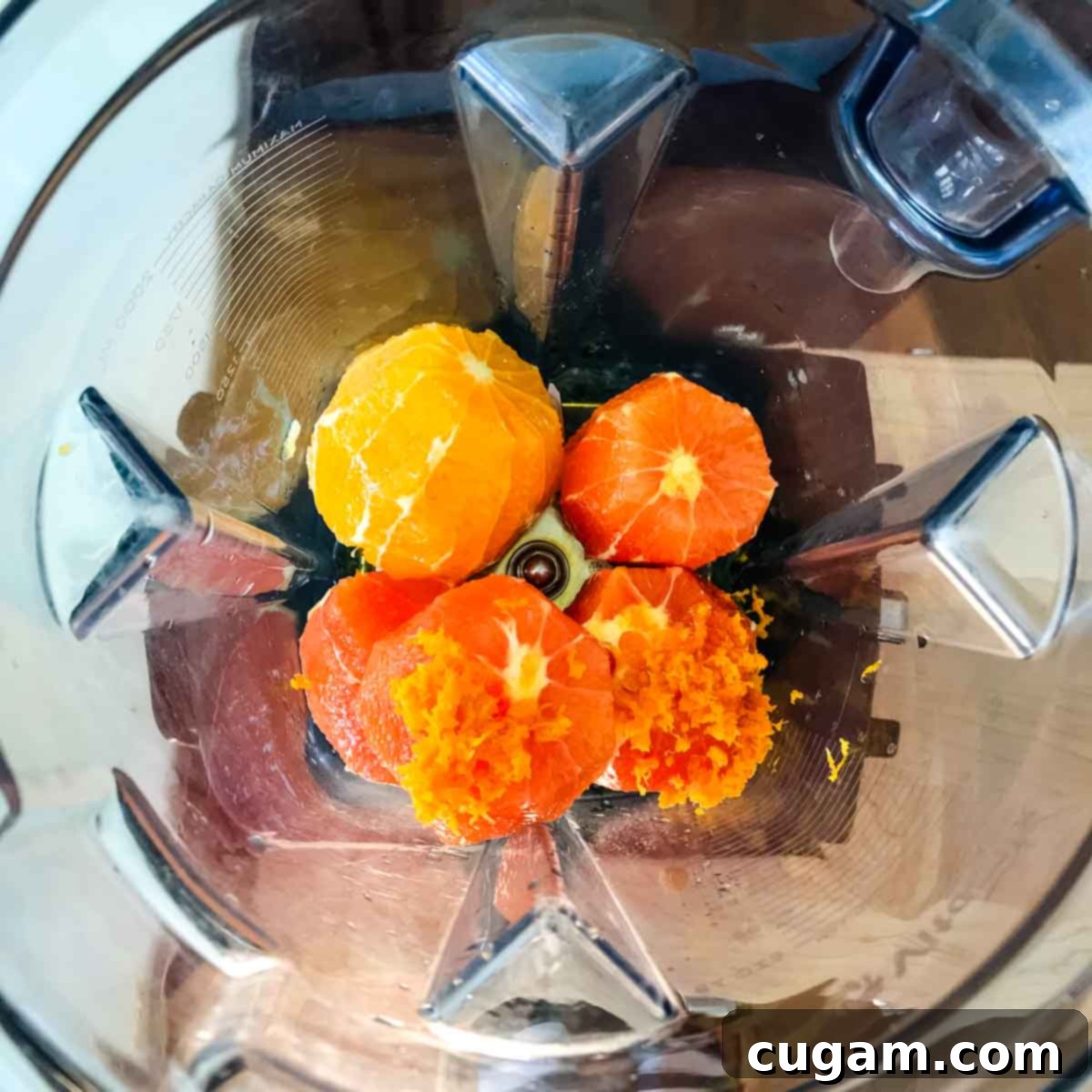 Whole, peeled oranges, plus orange zest in the pitcher of a blender.