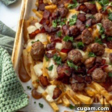 Metal pan with baked french fries, cheese, sausage, and bacon over parchment paper.