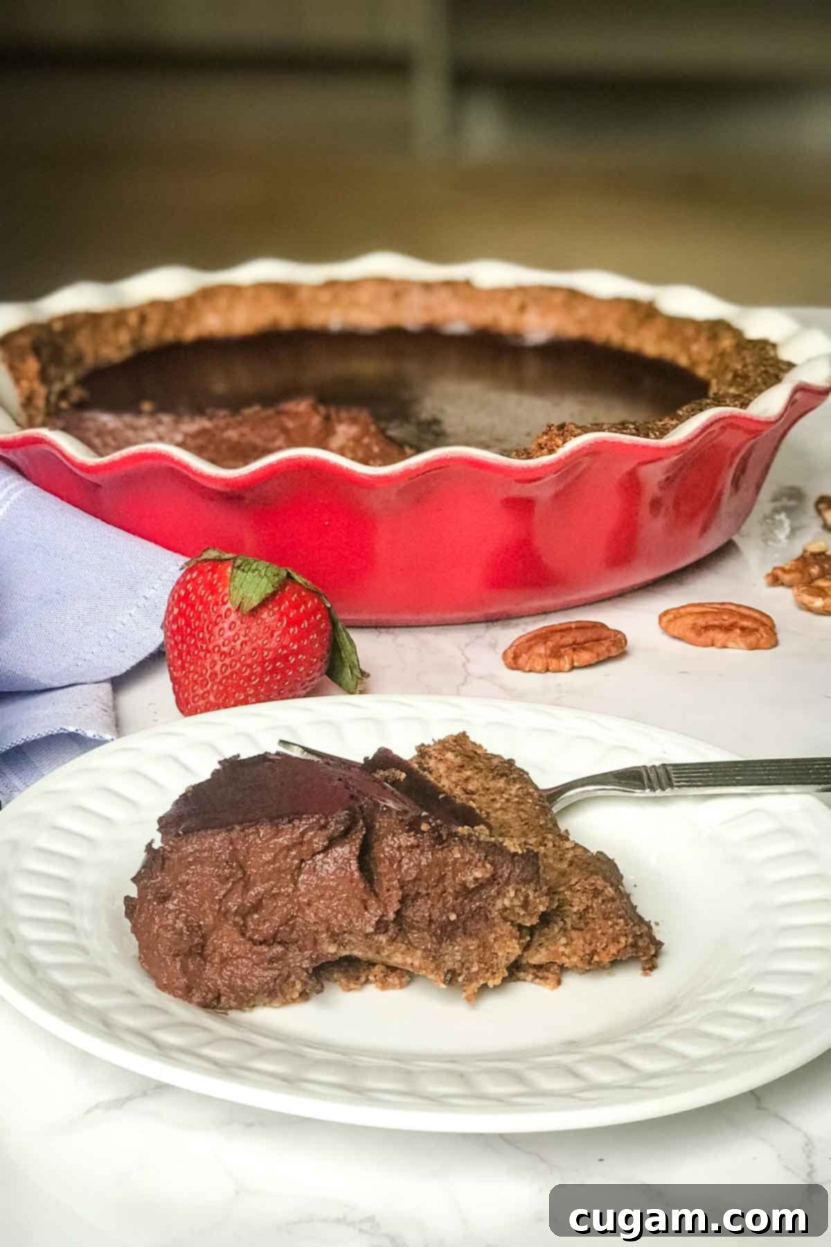 Side view of a slice of chocolate pudding pie, actual pie in the background.