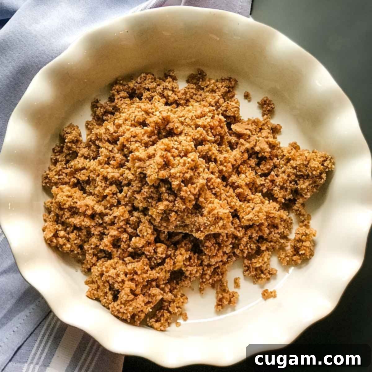 Crumbly date and nut mixture heaped in a pile inside a ceramic pie dish.