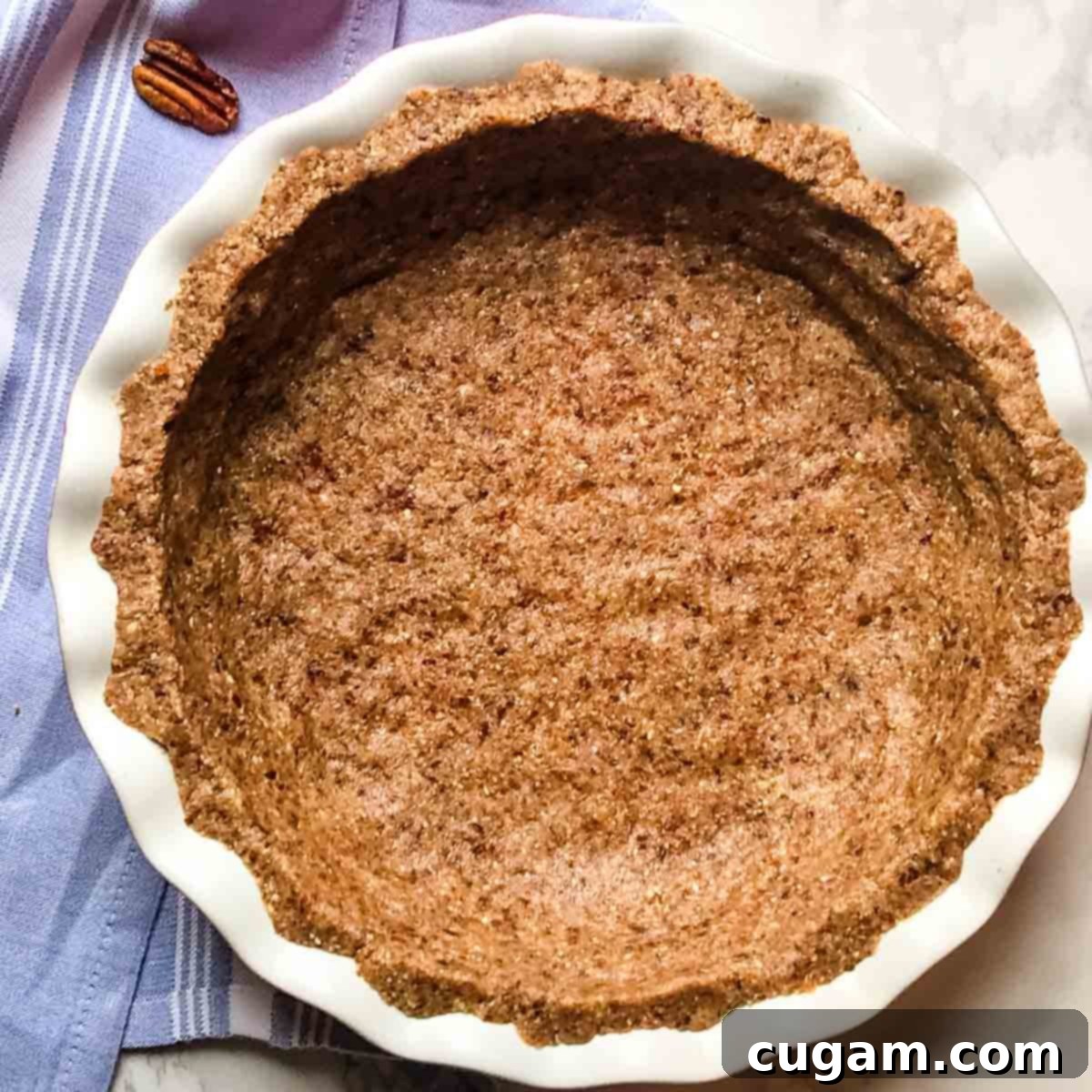 Nut and date pie crust inside a ceramic pie dish. 