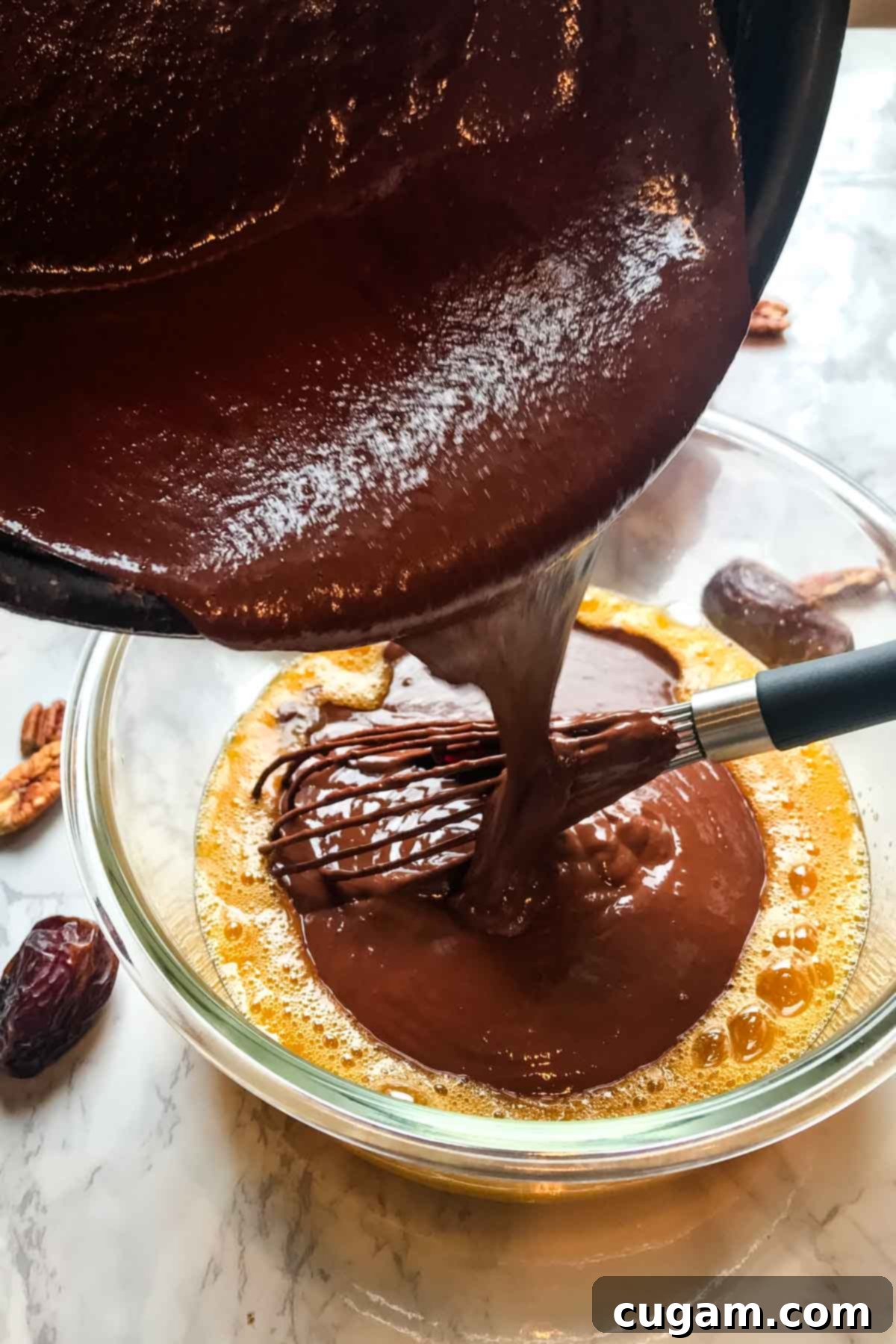 Indulgent Healthy Chocolate Pudding Pie 8 Pouring melted dark chocolate mixture into whisked eggs in a mixing bowl for the pie filling.