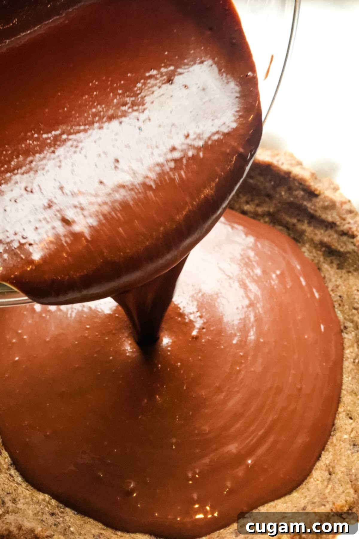 Pouring chocolate mixture into a nut pie crust.